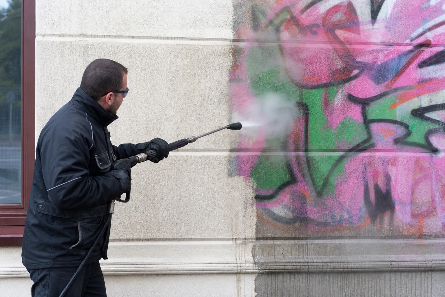 Mitarbeiter von Wertvoll Graffitientfernung entfernt Graffiti mit dem Heißwasser-Hochdruckverfahren von einer Fassade in Bielefeld